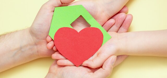 hands_holds_green_paper_house_with_red_heart